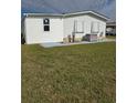 Rear view of a white manufactured home with a satellite dish and AC unit at 8479 Tanaka Dr, Englewood, FL 34224