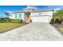 Charming one-story home with light-colored siding, orange door and gray paver driveway at 8960 Scallop Way, Placida, FL 33946