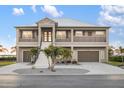 Elegant two-story home with a metal roof, dual garages, and a welcoming grand entrance with well-maintained landscaping at 9861 Eagle Preserve Dr, Englewood, FL 34224