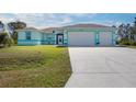 Charming single-story home with a three-car garage and a well-maintained lawn, accentuated by a bright color scheme at 12075 Duval Blvd, Port Charlotte, FL 33981