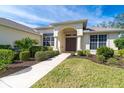 Landscaped front yard with a walkway leading to the arched entryway of a house at 12650 Montigello Ct, Englewood, FL 34223