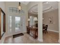 Bright and spacious entryway with a tiled floor, decorative console table, and view of the dining area at 13760 Long Lake Ln, Port Charlotte, FL 33953