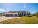 House exterior showcasing a three-car garage, manicured lawn and tile roof at 2 Windward Rd, Placida, FL 33946