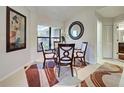 Cozy dining area featuring a round glass table with seating for four, a decorative mirror, and a modern area rug at 232 Southampton Ln # 259, Venice, FL 34293