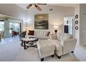 Bright living room featuring a white sofa and loveseat, a glass-top coffee table, and a ceiling fan for added comfort at 232 Southampton Ln # 259, Venice, FL 34293