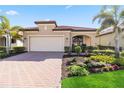 Tan one-story house with a paved driveway and lush landscaping at 24269 Spartina Dr, Venice, FL 34293