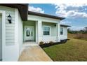 Front entrance with light green siding, white columns, and a welcoming porch at 7186 Rosemont Dr, Englewood, FL 34224