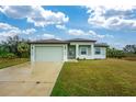 Curb appeal with light green house, attached garage, and spacious driveway at 7186 Rosemont Dr, Englewood, FL 34224