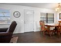 Bright dining area featuring a wood table, a large clock, and natural light from two windows at 1493 New Point Comfort Rd, Englewood, FL 34223