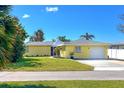 Charming single-story yellow home featuring a well-manicured lawn and attached garage at 275 North Dr, Englewood, FL 34223