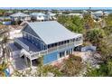 Beautiful blue two-story home with a metal roof, decks, and plenty of privacy surrounded by lush trees at 331 Bocilla Dr, Placida, FL 33946