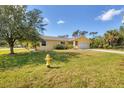 A quaint yellow home with an attached garage and green lawn at 6125 Higgins Ln, Englewood, FL 34224