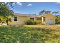 Yellow home with a green lawn and mature landscaping at 6125 Higgins Ln, Englewood, FL 34224