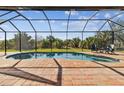 Inviting screened-in pool area with brick pavers, seating, and a view of lush greenery at 9533 Arnaz Cir, Port Charlotte, FL 33981