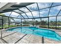A screened pool features a clear view of a calm canal and lush tropical foliage for tranquil relaxation at 9548 Applin Cir, Port Charlotte, FL 33981