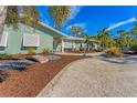 Single-story house with light green walls, white shutters, and a gravel driveway at 1080 Bayshore Dr, Englewood, FL 34223