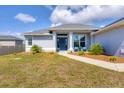 Inviting home exterior with a walkway, mulch beds, small palms, and blue chairs on the front porch at 13951 Allamanda Cir, Port Charlotte, FL 33981