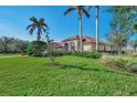 Manicured lawn with beautiful landscaping around this single Gathering home with a terracotta-colored tile roof at 14405 Silver Lakes Cir, Port Charlotte, FL 33953