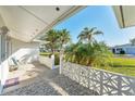 Cozy front porch with decorative concrete blocks, white gravel, and a view of mature palm trees at 1710 Loralin Dr, Englewood, FL 34223