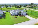 Aerial view of a charming home, a pond, lush landscaping, and a well-manicured lawn at 39 Medalist Cir, Rotonda West, FL 33947