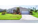 Well-maintained home with a spacious driveway, attached garage, and vibrant green lawn with decorative shrubbery at 39 Medalist Cir, Rotonda West, FL 33947