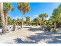 Landscaped entry to waterfront home with palm trees and shell driveway at 5 Pointe Way, Placida, FL 33946