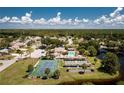 An aerial view of a community pool, tennis court, and amenity center surrounded by lush landscaping at 525 Foxwood Blvd, Englewood, FL 34223