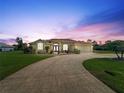 Inviting single Gathering home with lush landscaping, a paver driveway, and exterior lighting for evening appeal at 70 Sportsman Rd, Rotonda West, FL 33947