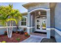Inviting front entry with double glass doors, manicured landscaping, and a tiled walkway at 15610 Seafoam Cir, Port Charlotte, FL 33981