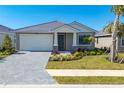 Inviting single-story home featuring a covered porch, well-manicured lawn, and a paver driveway, offering a warm welcome at 18575 Midsummer Pl, Venice, FL 34293