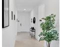 Bright hallway with a white door, tiled floor, and decorative art, enhanced by natural light and a stylish console table at 18575 Midsummer Pl, Venice, FL 34293