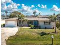 Charming single-story home with a well-manicured lawn, mature palm trees, and attached garage at 1910 Greenlawn Dr, Englewood, FL 34223