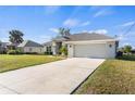 Wide concrete driveway leads to a light gray single-Gathering home with a well-kept lawn and landscaping at 23 Fairway Rd, Rotonda West, FL 33947