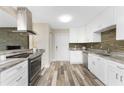 Bright kitchen featuring white cabinets, stainless steel appliances, granite countertops, and decorative backsplash at 1313 Buereau Rd, Englewood, FL 34223