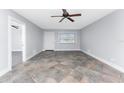 Bright living room with tiled floor, ceiling fan, and abundant natural light from the large window at 1918 Greenlawn Dr, Englewood, FL 34223