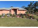 Attractive coral home with a well-manicured lawn, lush landscaping, and a decorative glass front door at 501 Cobalt Rd, Englewood, FL 34223