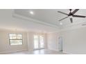 Inviting living room with tray ceiling, fan, and French doors, complemented by sleek flooring and ample natural light at 7282 Printer St, Port Charlotte, FL 33981