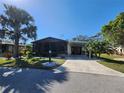 Charming home featuring a large screened sunroom, covered parking, manicured landscaping, and a long driveway at 810 Manchester Ct, Englewood, FL 34223