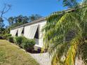 Home exterior featuring white siding, dark shutters, and manicured landscaping along the side of the home at 810 Manchester Ct, Englewood, FL 34223