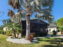 View of the screened sunroom from the front yard with a large palm tree in the foreground at 810 Manchester Ct, Englewood, FL 34223