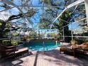 Inviting pool area with screened enclosure, wicker furniture, and tranquil water feature at 1108 Bayhead Ln, Osprey, FL 34229