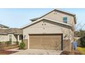 Two-story house with beige exterior, two-car garage, and landscaping at 10710 Southern Forest Dr, Riverview, FL 33578