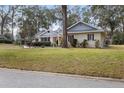 Brick home with a tree-lined front yard and street view at 12631 Timber Run, Dade City, FL 33525