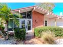 Mid-century home's entrance with brick facade, double doors and lush landscaping at 8280 140Th St, Seminole, FL 33776