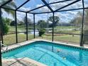 Screened-in pool overlooking a serene lake, perfect for relaxation and entertainment at 7644 Arlight Dr, New Port Richey, FL 34655