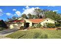 Single-story house with red tile roof, lush landscaping, and a paved driveway at 3633 Nettle Creek Ct, Holiday, FL 34691