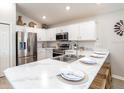 Modern kitchen with white cabinets, marble countertops, and stainless steel appliances at 6015 Mangrove Creek Rd, Wimauma, FL 33598