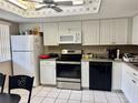 Well-lit kitchen featuring white cabinets, appliances, and neutral countertops at 11231 Dollar Lake Dr # 1, Port Richey, FL 34668