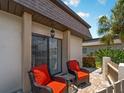 Relaxing patio with two red chairs and a small table, next to sliding glass doors at 1708 Lakeside Dr # 1710-B, Venice, FL 34293