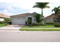 Single story house with a two car garage, front yard, and palm trees at 11684 Renaissance Blvd, Venice, FL 34293